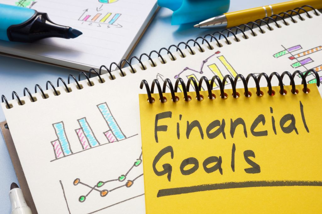 Notepad with financial goals surrounded by charts and graphs