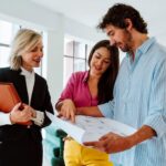 Couple discussing a real estate purchase with a professional while reviewing property plans.