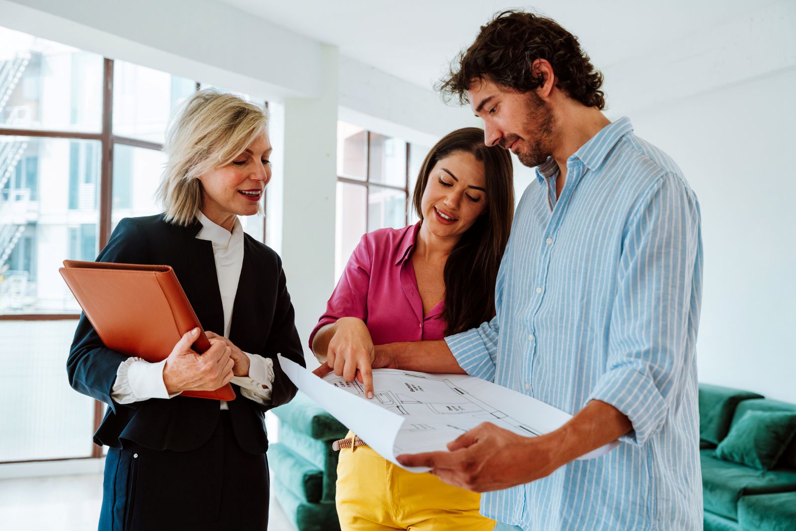 Couple discussing a real estate purchase with a professional while reviewing property plans.